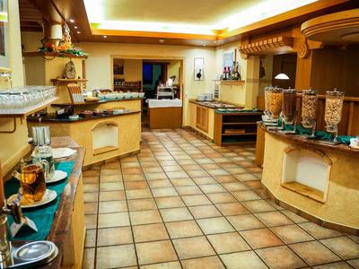 Großer Frühstücksraum mit Bodenfliesen, Theken, Cafemaschine und verschiedenen Frühstückszutaten.