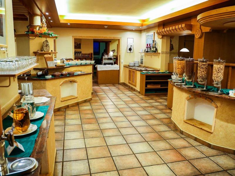 Großer Frühstücksraum mit Bodenfliesen, Theken, Cafemaschine und verschiedenen Frühstückszutaten.