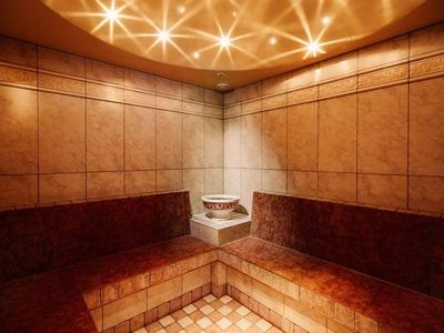 Warm, cozy sauna room with wood-paneled walls and orange lighting.