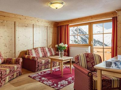 Cozy living room with wooden walls, checkered furniture, and mountain view.