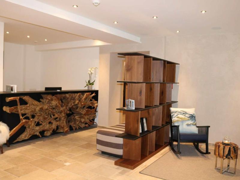 Modern hotel lobby with wooden reception desk, partition shelf, armchairs, and warm inviting design.