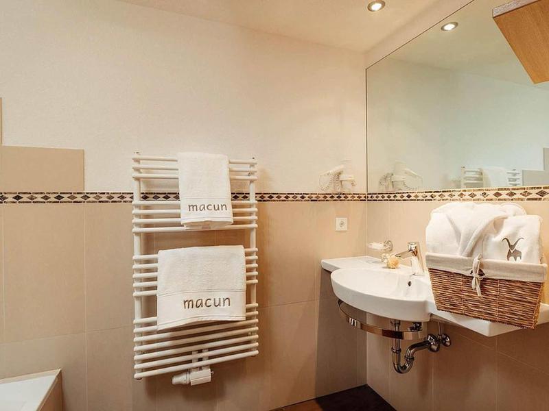 Modern bathroom with white towels on radiator and laundry basket.