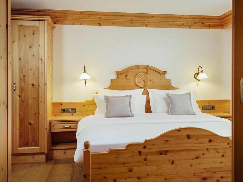 Cozy hotel room with double bed and rustic wooden furniture.