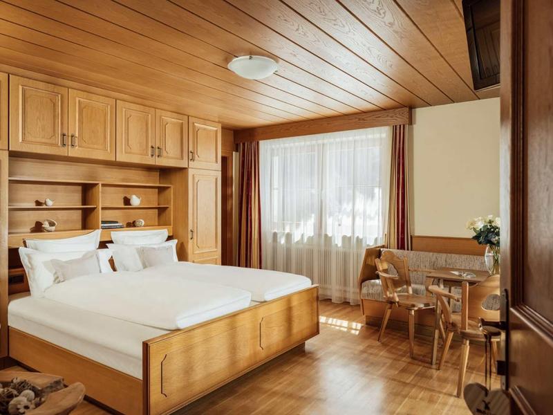 Cozy hotel room with wooden furniture, large bed, and a desk by the window.