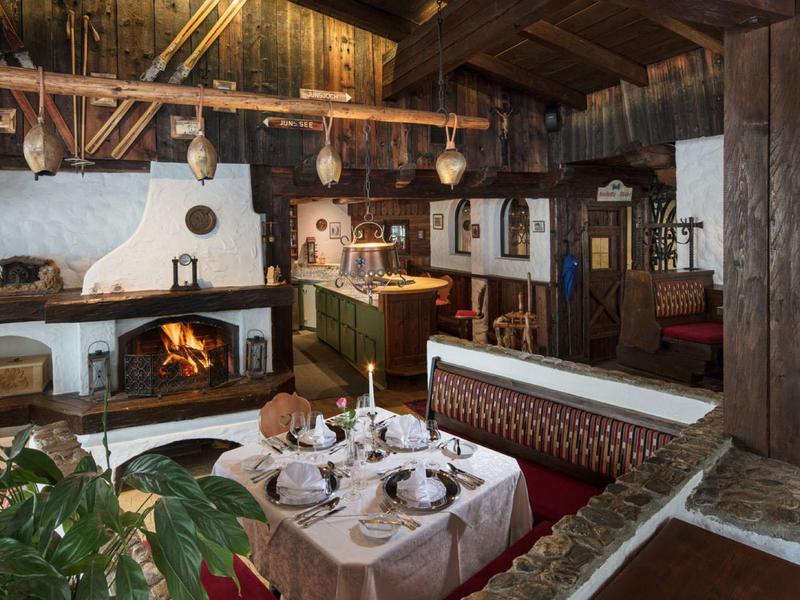 Gemütliches rustikales Esszimmer mit Holzbalken, Kamin, gedecktem Tisch und warmem Licht.