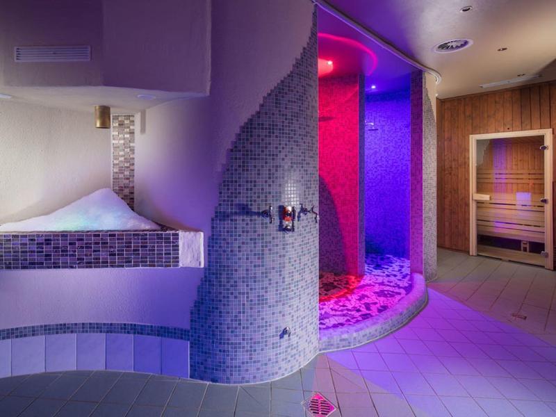 Moderner Wellnessbereich mit Mosaikdusche, Sauna, warmem Holz und beruhigender Beleuchtung.