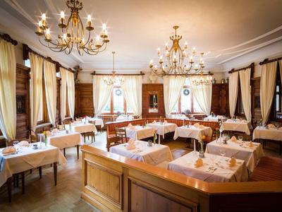 Festlich gedeckter Speisesaal mit Kronleuchtern, hellen Vorhängen und elegantem Holzmobiliar.