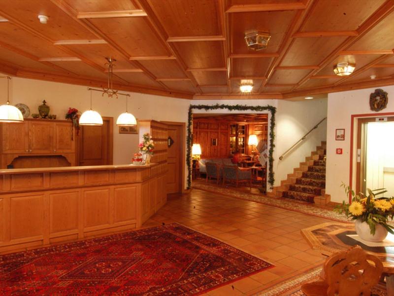 Gemütlicher holzinterieur Empfangsbereich mit Teppichen, Treppe und warmem Licht.