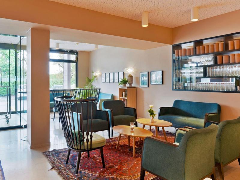 Gemütliches Wohnzimmer mit blauen Sesseln, Sofa, Holzmöbeln und großem Teppich in warmen Tönen.