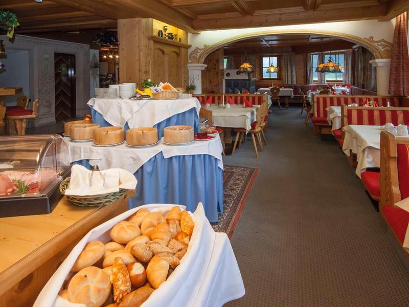 Bäckerei mit Körben voller Brötchen und gedeckten Tischen in warmem, rustikalem Raum.