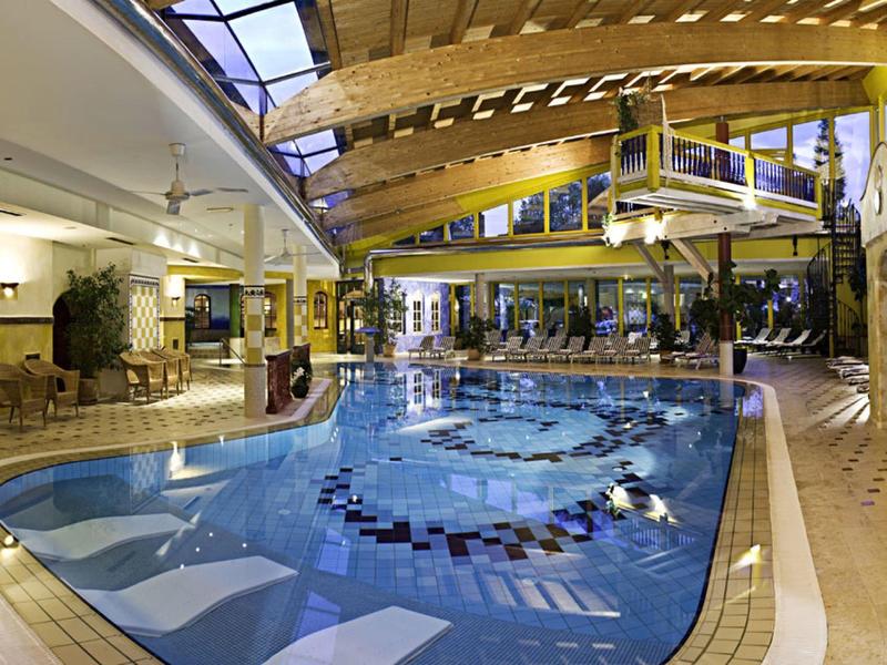 Innenbereich eines Hotels mit großem Schwimmbad und Holzdecke.