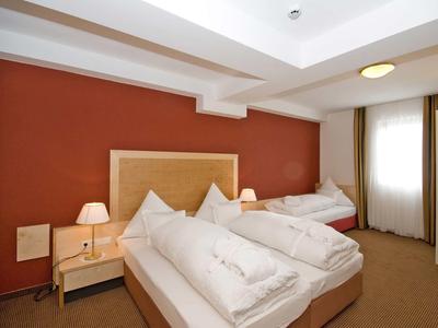 Modern hotelkamer met twee eenpersoonsbedden, rode muur en bedlampen.