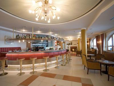 Elegante hotelbar met ronde balie, rode leren stoelen en bijpassende fauteuils.