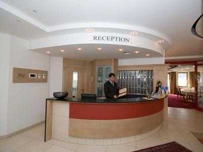 Moderne Rezeption mit runder Theke, zwei Mitarbeitern und heller, eleganter Innenraumgestaltung.