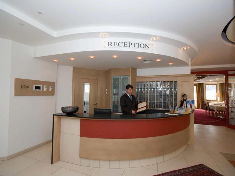 Moderne Rezeption mit runder Theke, zwei Mitarbeitern und heller, eleganter Innenraumgestaltung.