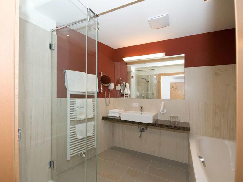 Moderne Badezimmer mit Glas-Duschkabine, langem Spiegel, weißem Waschbecken und braunen Wänden.