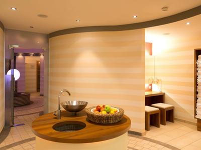 Moderner Wellnessraum mit runder Holzbank, Obstkorb und Handtüchern an der Wand.