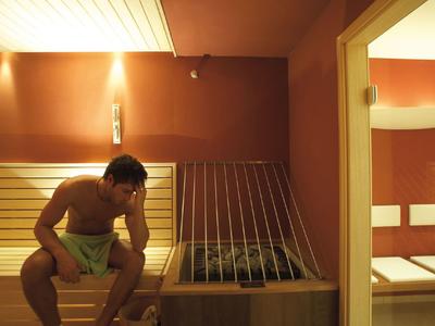 Ein Mann entspannt in einer Sauna mit Holzverkleidung und gedämpftem Licht.