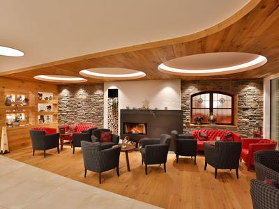 Pohodlná hotelová lobby s krbem, dekorativními kamennými zdmi a pohodlnými křesly.