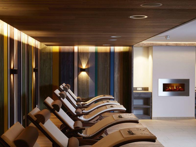 Ruheraum mit bequemen Liegen und modernem Kamin in warmem Licht.