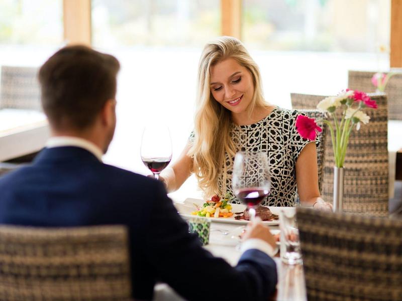 Runder Spa-Bereich mit zentralem beleuchtetem Brunnen und zwei Gästen in Bademänteln.