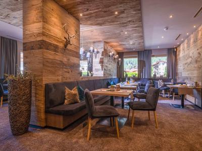 Gemütlicher Hotel-Loungebereich mit Holzwänden, Polstermöbeln und großen Fenstern.