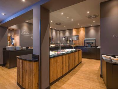 Moderne Hotelküche mit Holzakzenten, integrierten Geräten und indirekter Beleuchtung.