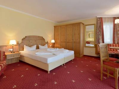 Gemütliches Hotelzimmer mit Doppelbett, Holzmöbeln und rotem Teppichboden.