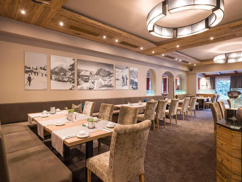 Gemütlicher Speiseraum mit Holzbalkendecke, bequemen Stühlen und Tischen im Restaurant.