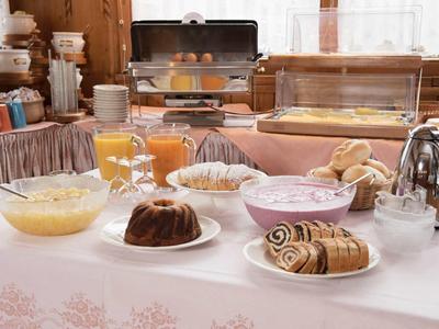 Breakfast buffet with pastries, cake, juice, and yogurt in a cozy setting.