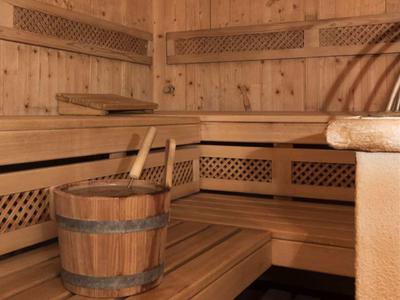 Wooden sauna with benches, bucket, and ladle in a warm, cozy atmosphere.