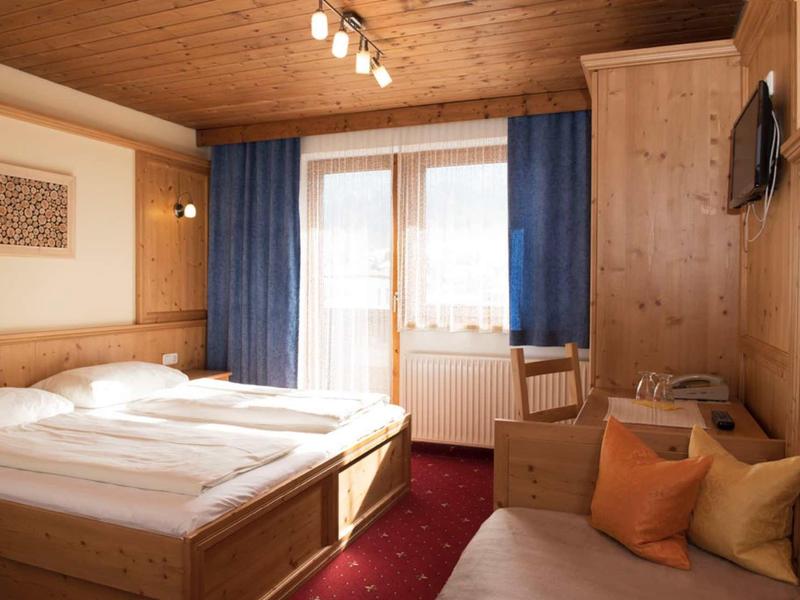 Cozy hotel room with wooden furniture, double bed, and seating area with colorful cushions.