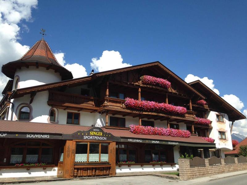 Traditional hotel with flower-decorated balconies under a blue sky.
