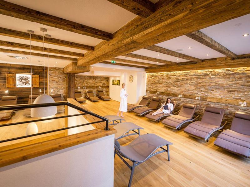 Gemütlicher Wellnessraum mit Holzbalken, Liegestühlen und warmem Holzfußboden.
