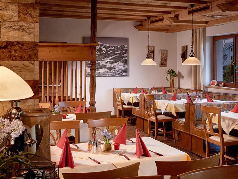 Gemütliches Restaurant mit Holzmöbeln, karierten Tischtüchern und rot gefalteten Servietten.