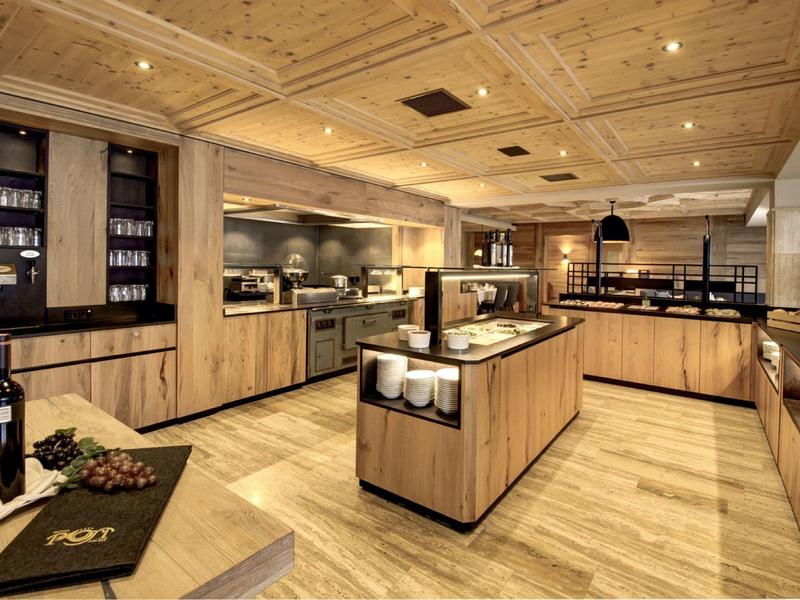 Moderne Küche mit Holzdecke, Arbeitsinsel, Edelstahlgeräten und warmem Holzbodenbeleuchtung.