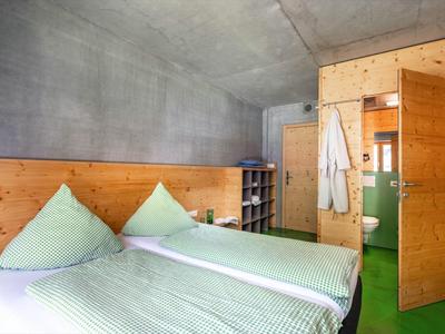 Cozy double room with two single beds, green bedding, and wooden furniture.