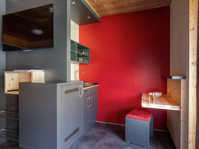 Modern kitchenette with red wall and wood-clad dining nook in a small space
