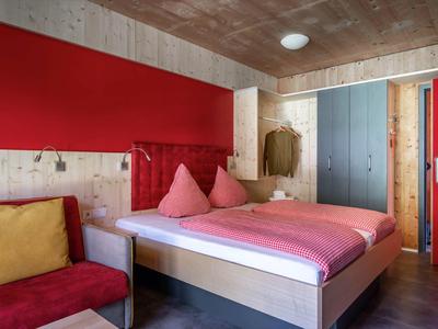 Cozy room with a bed, colorful walls, and a chair with cushions.