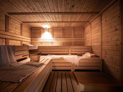 Cozy sauna with wooden benches, lighting, and sauna bucket.