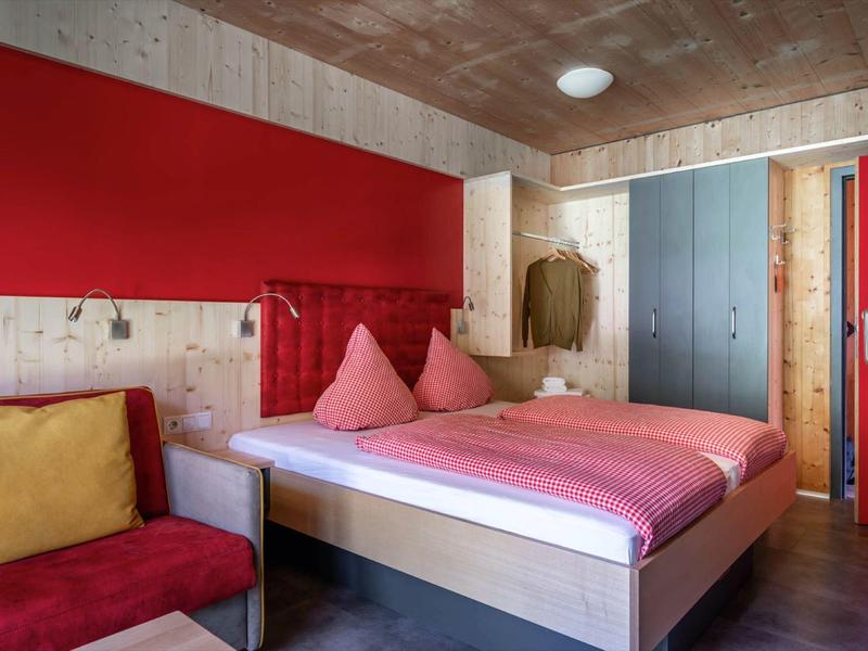 Cozy room with a bed, colorful walls, and a chair with cushions.