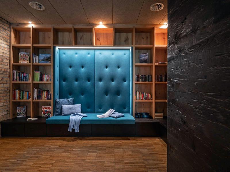Cozy reading nook with tall, tufted blue seating nook and bookshelves in the background.