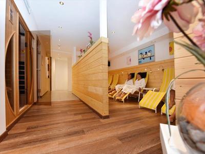 Moderner Flur mit Holzverkleidung, Holzboden und Sitzbereich mit gelben Liegen und Blumendeko.