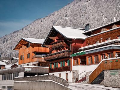 Holzchalets mit Schneebedeckung in einem Bergdorf bei klarem Himmel.