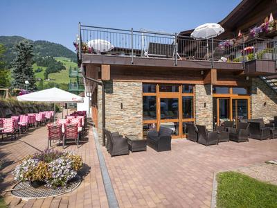 Buitengebied van hotel met zitplaatsen, parasols en uitzicht op bergen