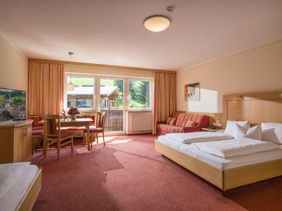 Ruime hotelkamer met twee bedden, zithoek en groot raam met uitzicht.