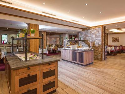 Großer, heller Speisesaal mit Holztheken, warmem Licht und rustikalem Ambiente.