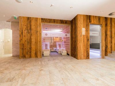 Moderner Spa-Bereich mit Holzverkleidung, Sauna, Dampfbad und hellem Marmorfußboden.