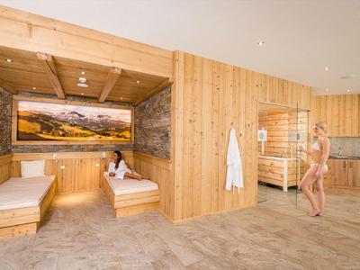 Moderner Wellnessraum mit Holzvertäfelung, Steinakzenten, Liegen und großer Panoramabild-Wanddekoration.