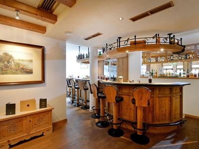 Gezellige hotelbar met houten balie, barkrukken en warme verlichting.